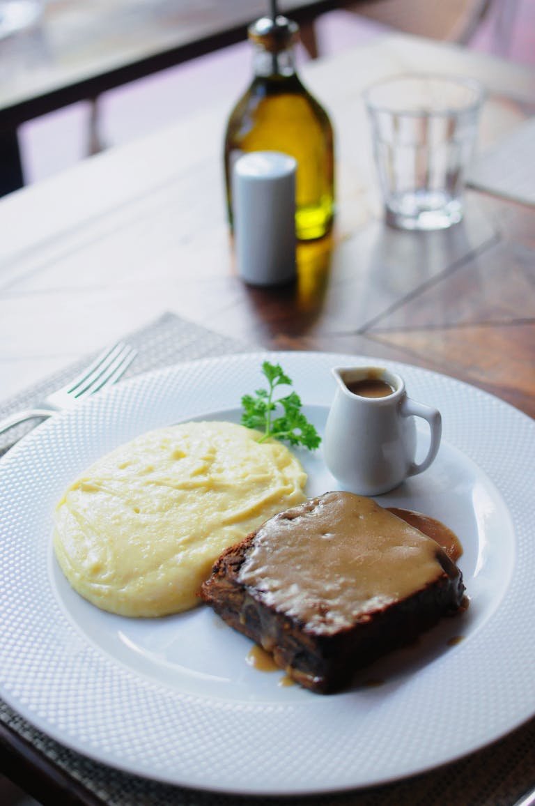 A tasty dish of homemade meatloaf with creamy mashed potatoes served with gravy on a white plate.