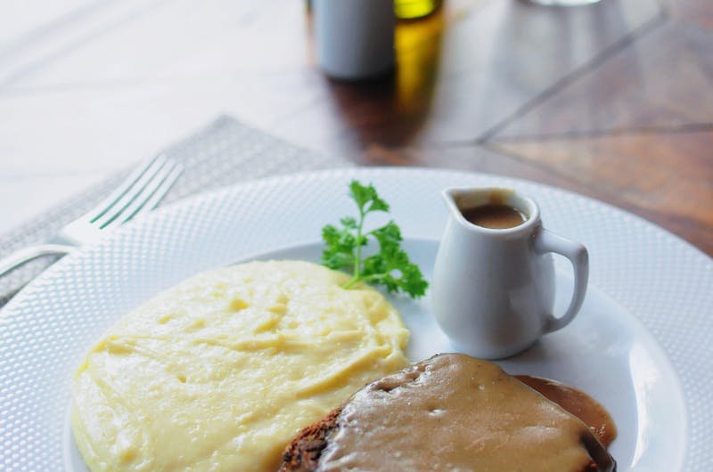 A tasty dish of homemade meatloaf with creamy mashed potatoes served with gravy on a white plate.