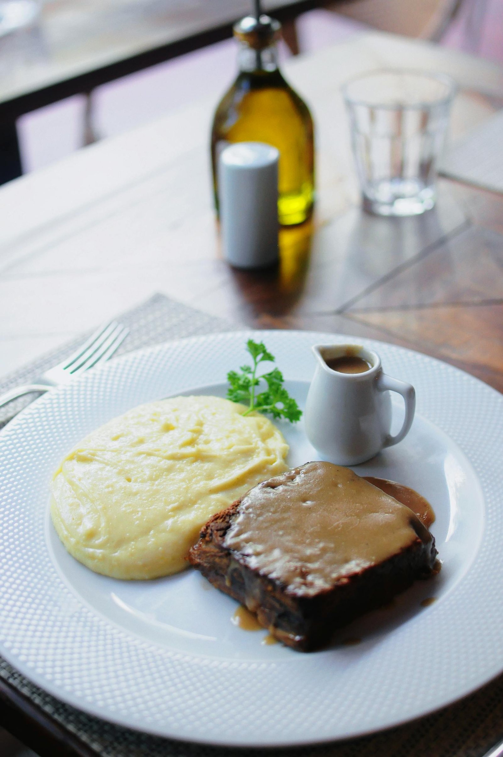 A tasty dish of homemade meatloaf with creamy mashed potatoes served with gravy on a white plate.