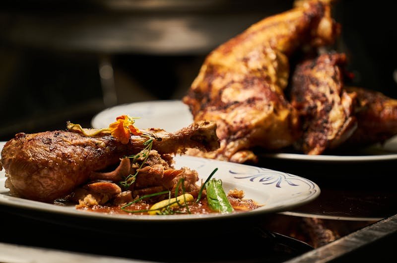 Close-up of a deliciously roasted chicken dish served with garnish, highlighting fine cuisine.
